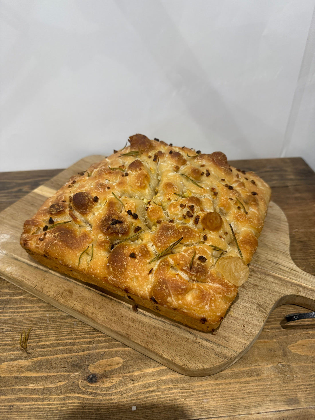 Garlic and rosemary foccacia on a wooden chopping board.